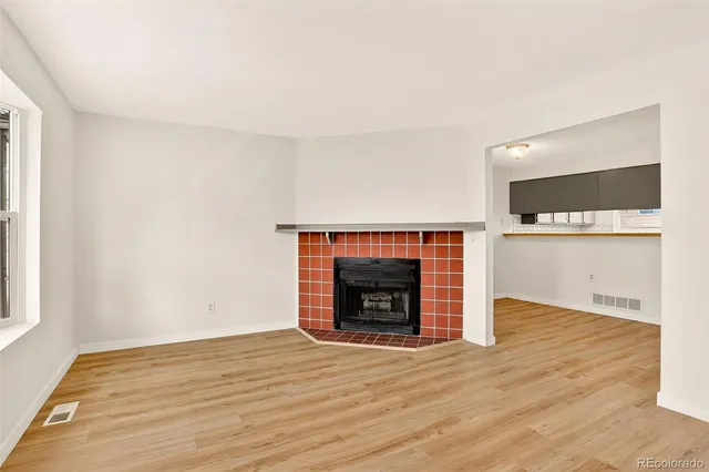 a view of empty room with wooden floor and a fireplace