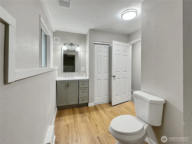 a bathroom with a toilet a sink a mirror and vanity