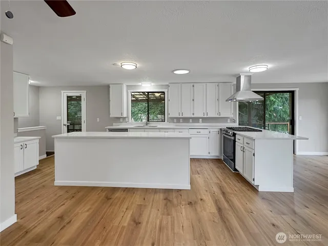 a large kitchen with cabinets wooden floor and stainless steel appliances
