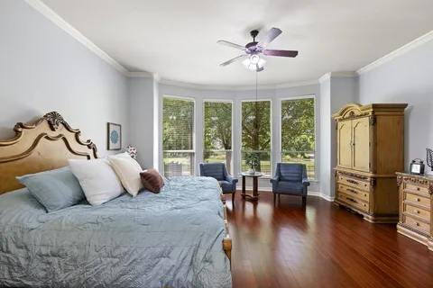 a bedroom with furniture large window and wooden floor