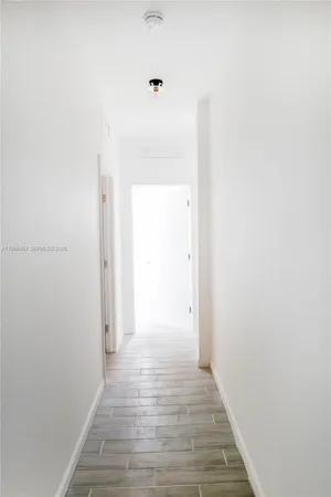 an empty room with wooden floor cabinet and windows