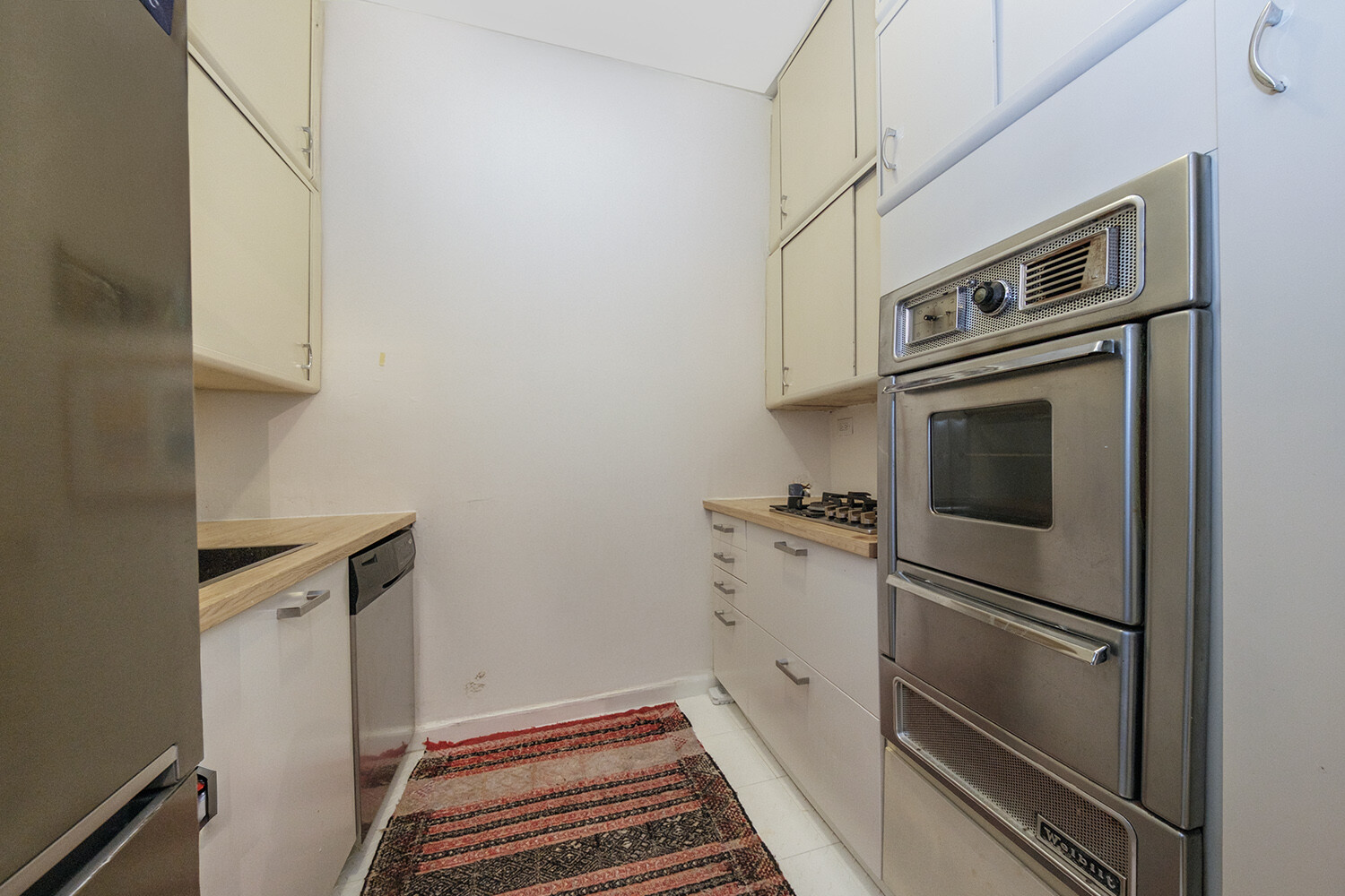 25 East 69th Street, Unit 5B Manhattan, NY 10021 - Photo 9 of 22 a kitchen with cabinets and steel appliances