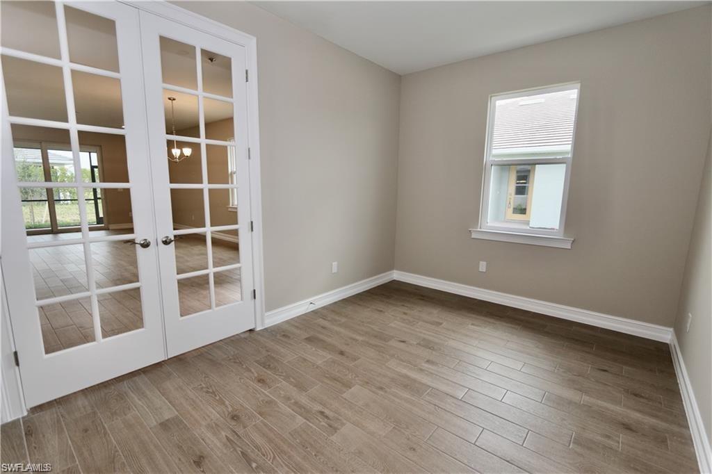 1063 Enbrook Loop Naples, FL 34114 - Photo 12 of 26 an empty room with wooden floor and windows