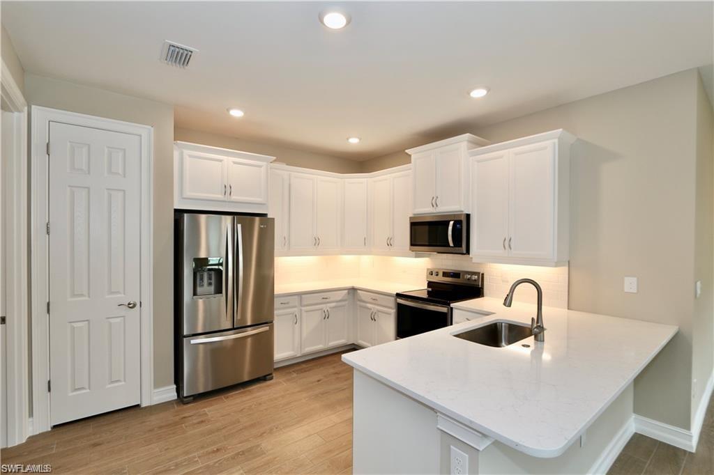 1063 Enbrook Loop Naples, FL 34114 - Photo 5 of 26 a kitchen that has a sink a refrigerator and cabinets
