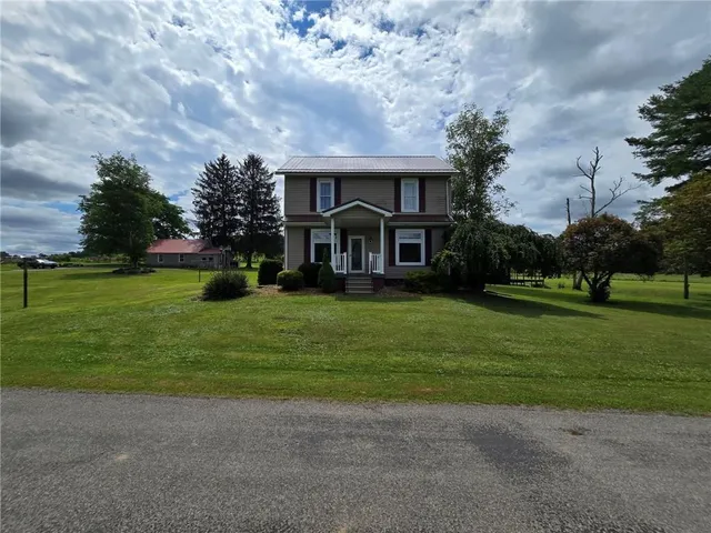 a front view of a house with garden and trees