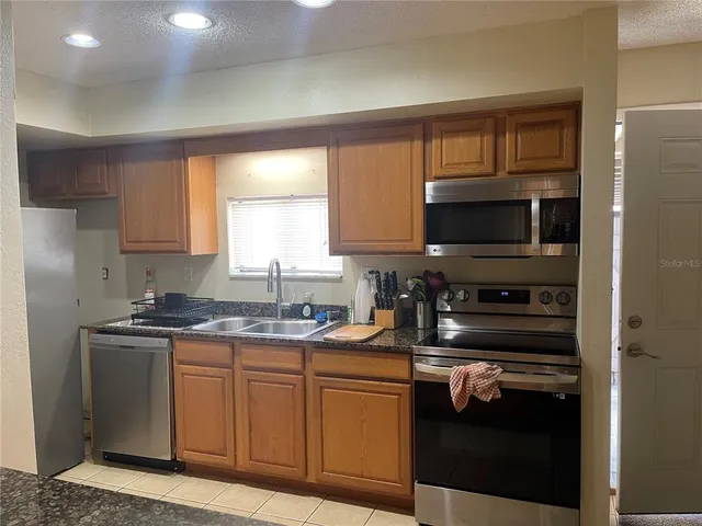 a kitchen with stainless steel appliances granite countertop a stove a sink and a microwave