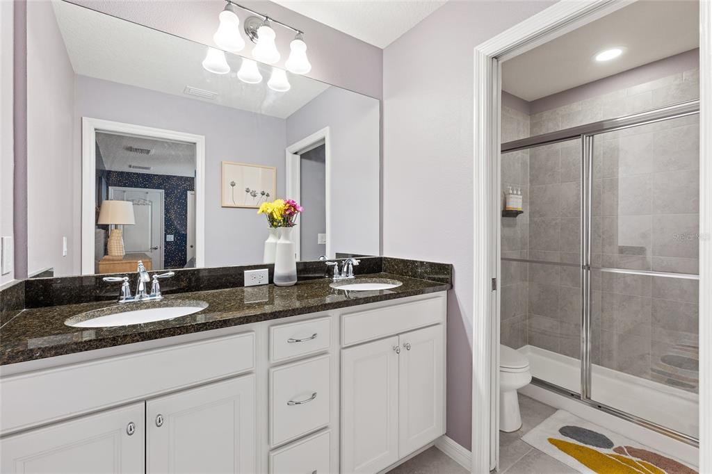 1864 Nice Court Kissimmee, FL 34747 - Photo 29 of 35 a bathroom with a granite countertop sink a mirror and a shower