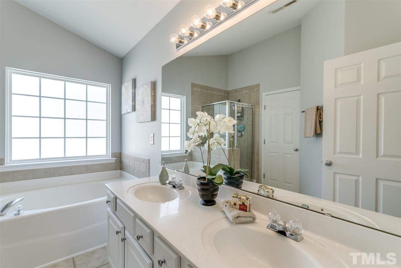 8404 Whisper Ridge Place Raleigh, NC 27613 - Photo 20 of 25 a bathroom with a tub a sink and mirror