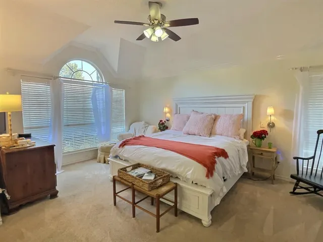 a spacious bedroom with a bed a chandelier and a dresser
