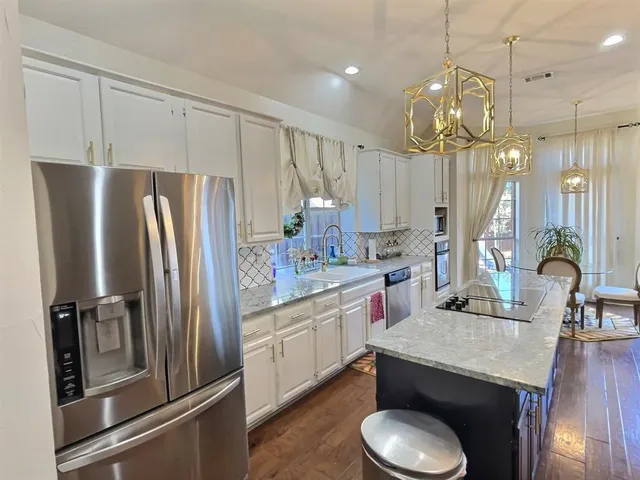 a kitchen with stainless steel appliances a dining table chairs and wooden floor