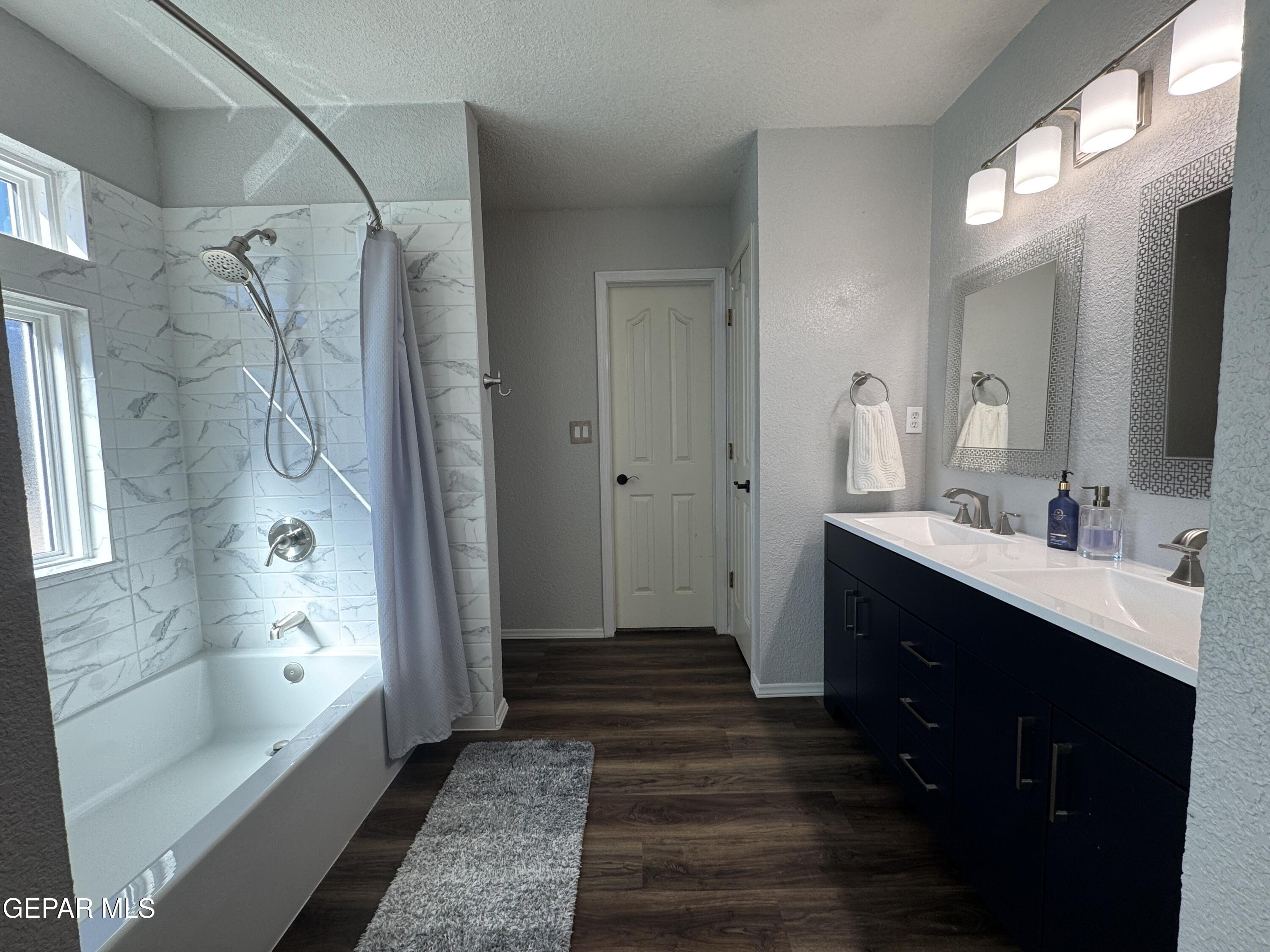 4621 Esparza Lane El Paso, TX 79934 - Photo 15 of 24 a bathroom with a double vanity sink a large mirror a bathtub and shower