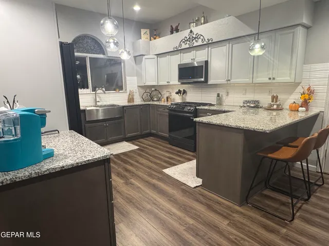 a kitchen with kitchen island granite countertop a sink cabinets and stainless steel appliances