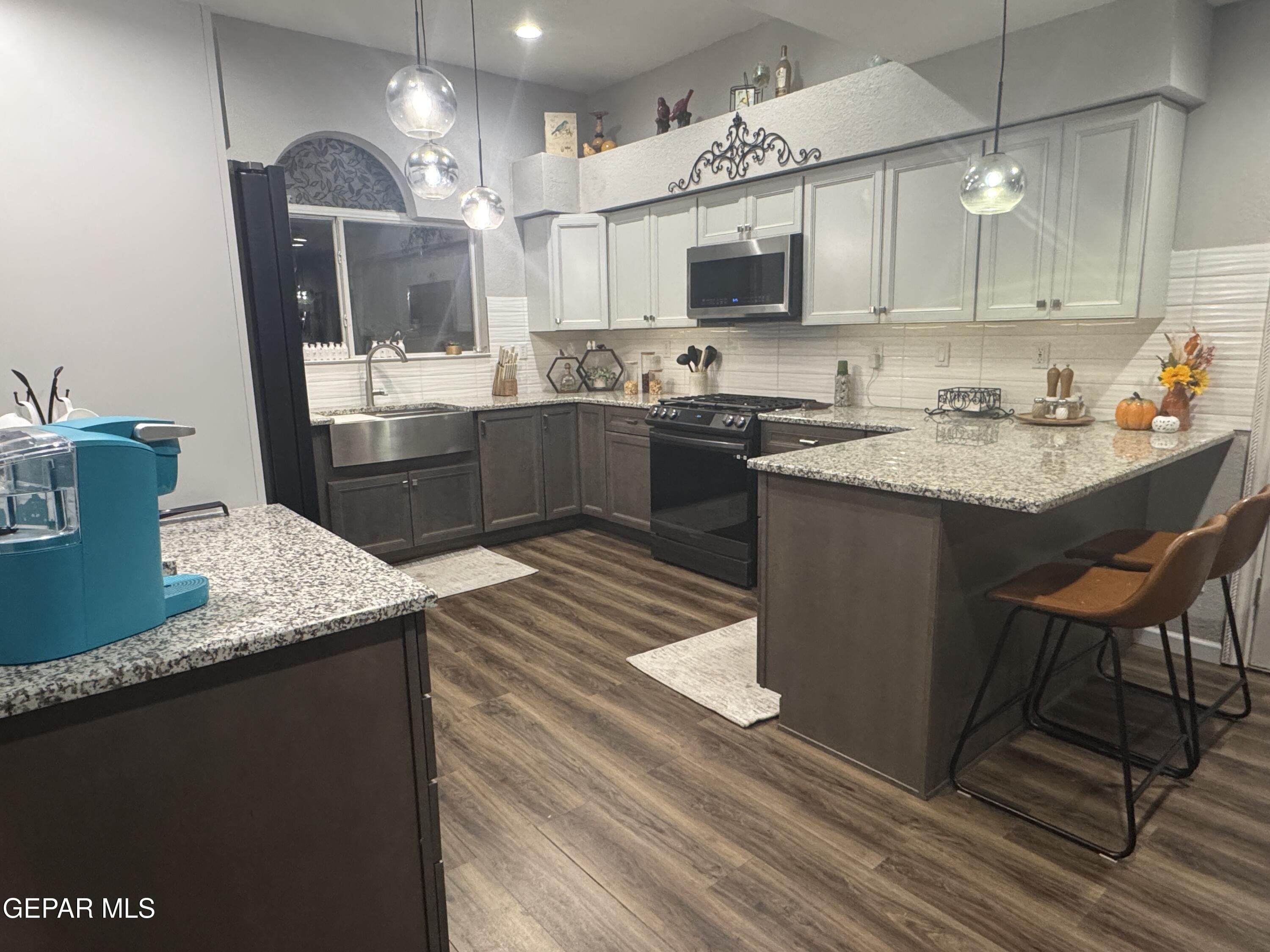 4621 Esparza Lane El Paso, TX 79934 - Photo 6 of 24 a kitchen with kitchen island granite countertop a sink cabinets and stainless steel appliances