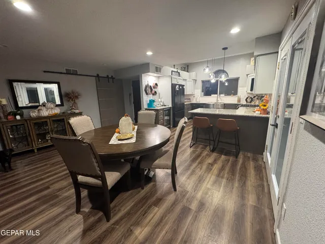 a kitchen with a dining table chairs and refrigerator