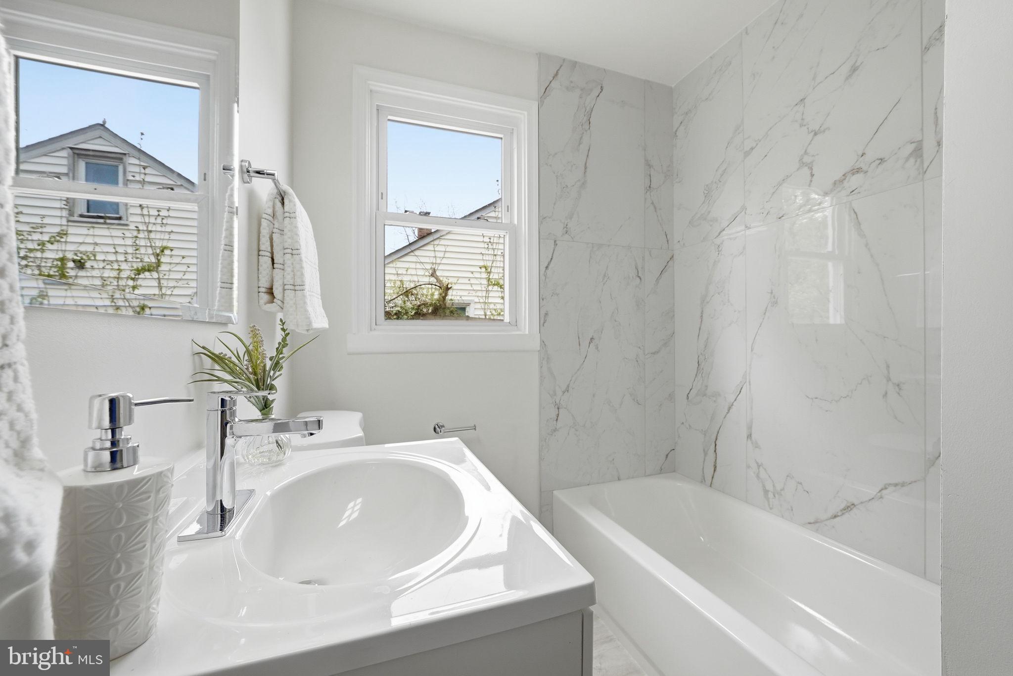 12304 Livingston Street Silver Spring, MD 20902 - Photo 17 of 20 a white bath tub sitting next to a white sink and a mirror