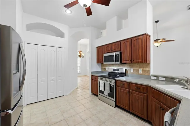 a kitchen with stainless steel appliances granite countertop a refrigerator a stove a sink and dishwasher with wooden cabinet