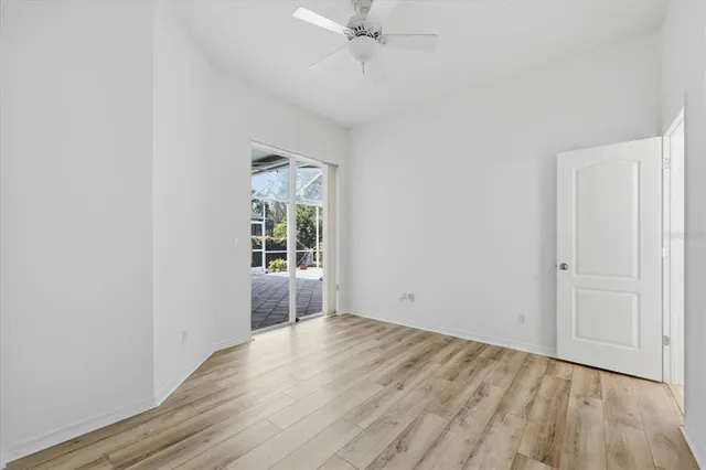 an empty room with wooden floor closet and windows