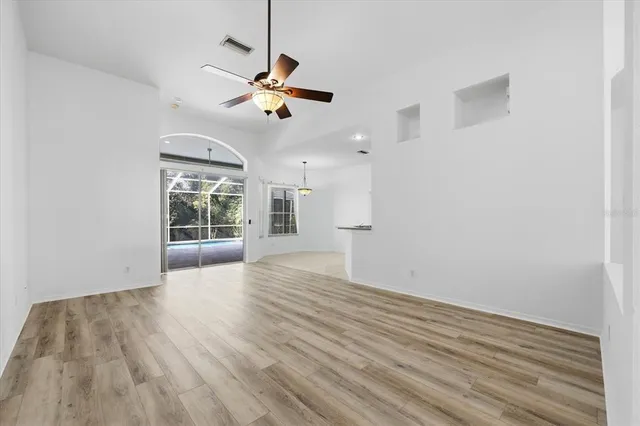 a view of empty room with wooden floor and ceiling fan