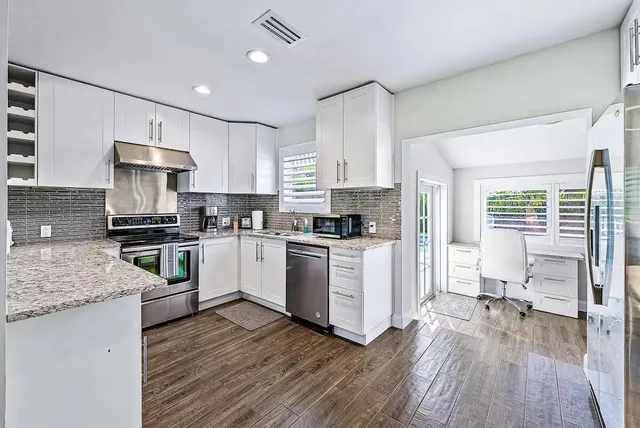 a kitchen with granite countertop a sink stainless steel appliances and cabinets