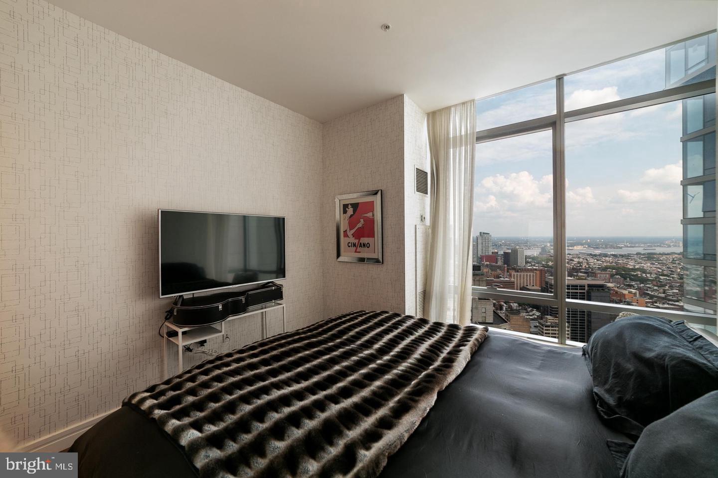 1414 South Penn Square, Unit 45A Philadelphia, PA 19102 - Photo 19 of 23 a living room with a couch a flat screen tv and a floor to ceiling window