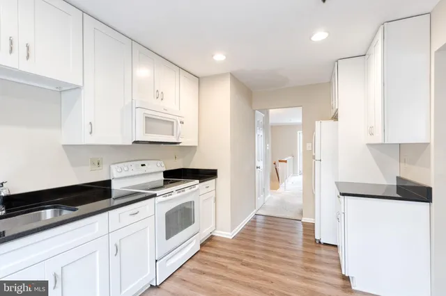 a kitchen with granite countertop white cabinets and white appliances