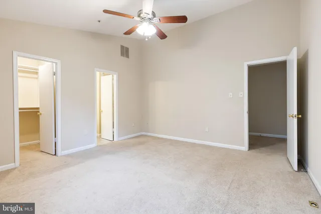 an empty room with closet and a ceiling fan