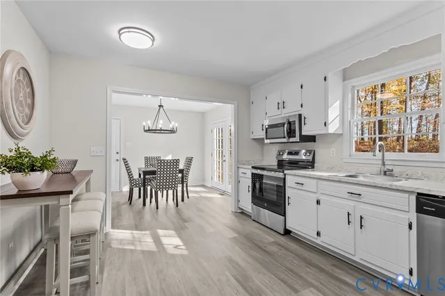a kitchen with granite countertop stainless steel appliances a dining table and chairs