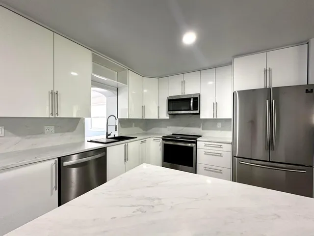 a large kitchen with stainless steel appliances a large window and a refrigerator