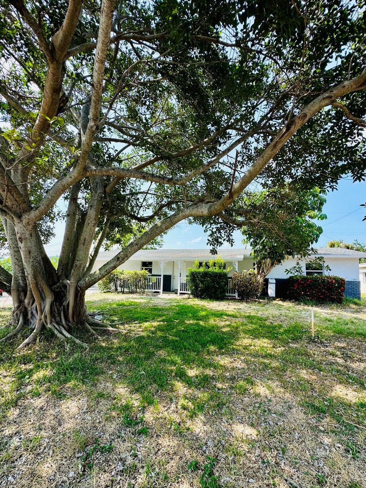 1455 Northeast Silver Maple Way Jensen Beach, FL 34957 - Photo 54 of 55 a front view of a house with a yard