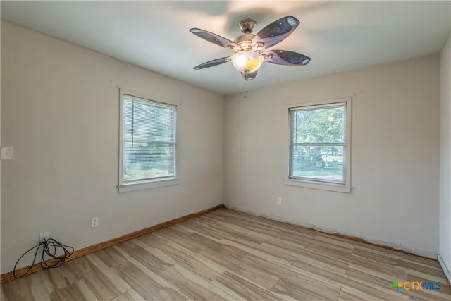 a view of an empty room with a window and wooden floor