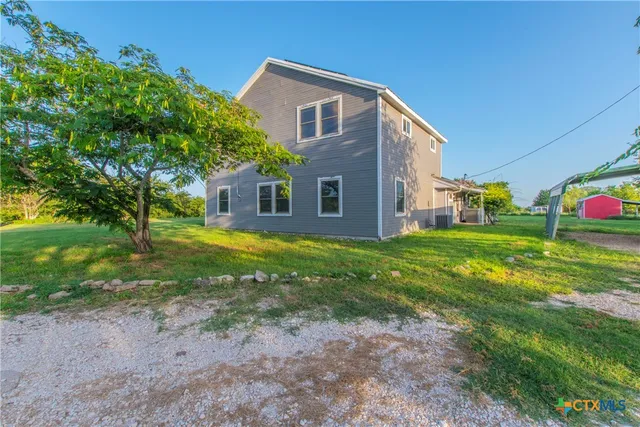 a view of a house with a big yard and large trees