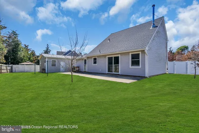 a backyard of a house with table and chairs plants and large tree