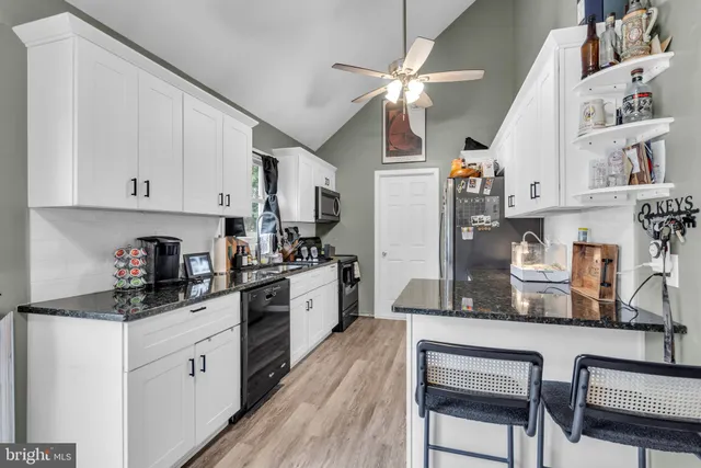 a kitchen with stainless steel appliances white cabinets and wooden floor