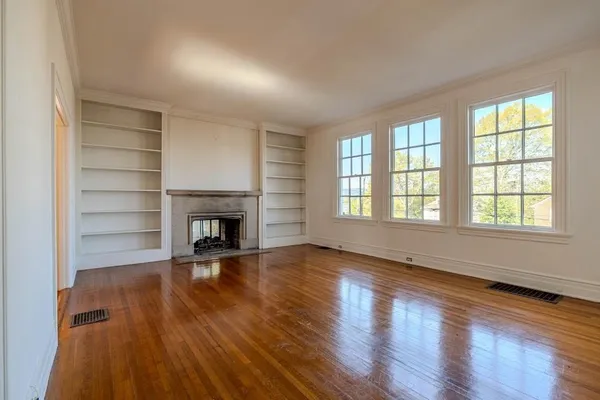 wooden floor fireplace and windows in an empty room