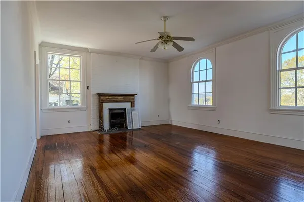 an empty room with wooden floor fireplace and windows