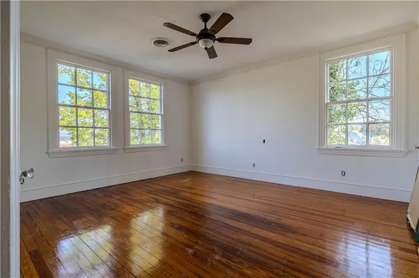 a view of an empty room with window and wooden floor
