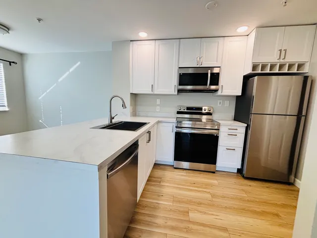 a kitchen with a sink a microwave a refrigerator and cabinets