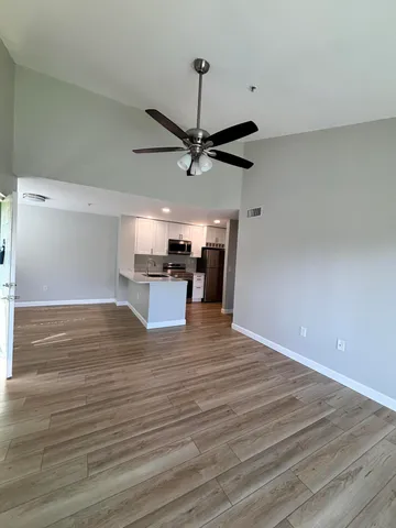 a view of kitchen and empty room with wooden floor