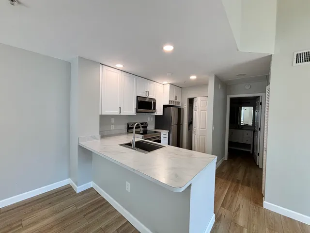 a kitchen with a sink a counter top space stainless steel appliances and cabinets