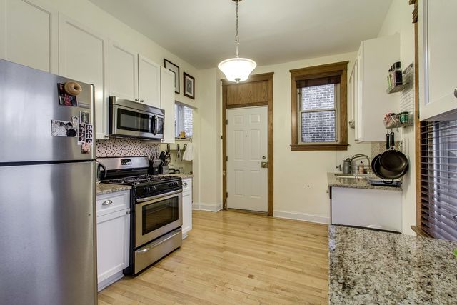 a kitchen with stainless steel appliances granite countertop a sink a stove a refrigerator cabinets a refrigerator and a stove