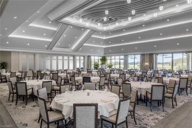 a room with lots of tables a large window and chairs