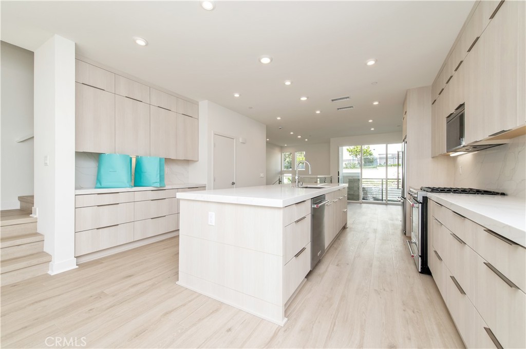 2604 Everly Drive San Diego, CA 92108 - Photo 10 of 33 a large white kitchen with kitchen island a large counter top space a sink stainless steel appliances and cabinets