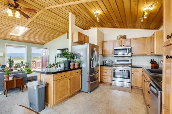 a kitchen with stainless steel appliances kitchen island granite countertop a table chairs and a refrigerator