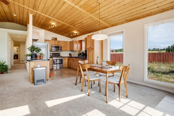a dining hall with stainless steel appliances a dining table wooden floor and a large window
