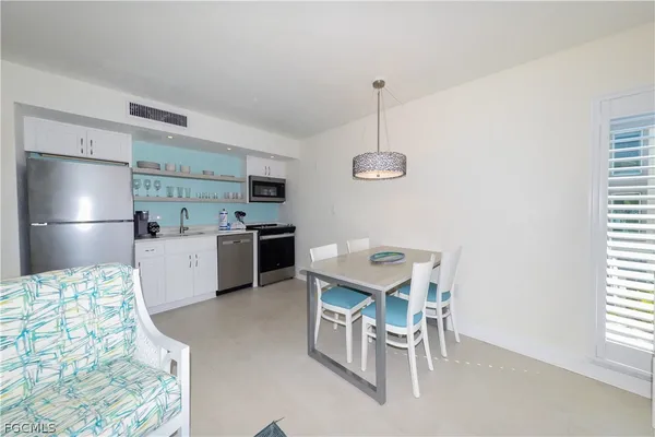 a kitchen with a sink a refrigerator and chairs