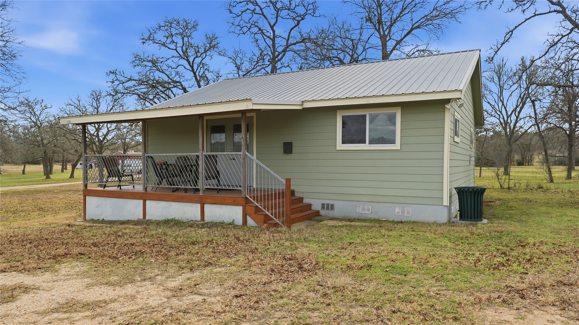 View of front of house featuring crawl space, a front yard, covered porch, a metal roof, and french doors