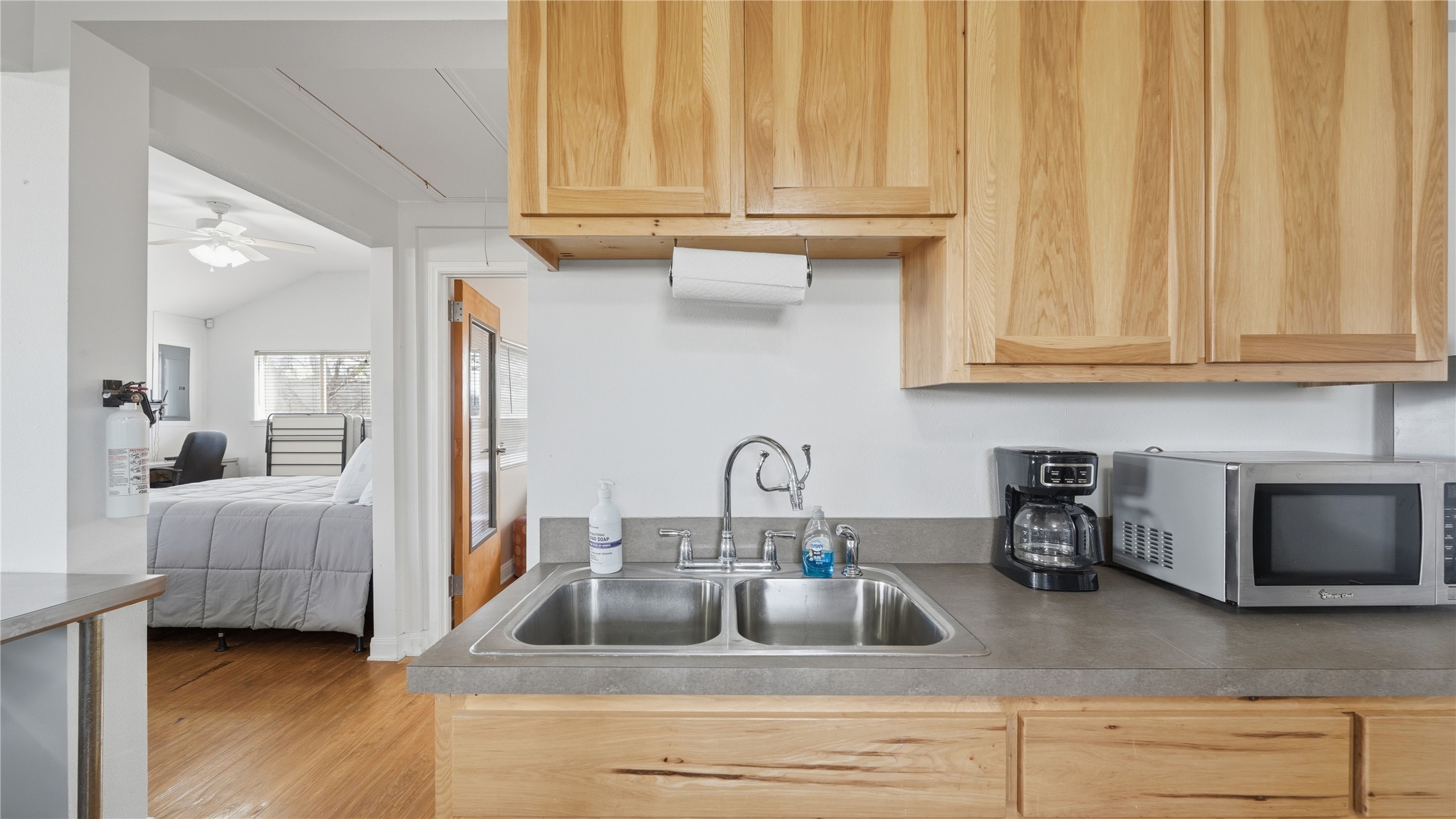 218 Little Ranch Road, Unit E Red Rock, TX 78662 - Photo 13 of 22 Kitchen featuring light wood finish cabinets, stainless steel microwave, ceiling fan, and wood finished floors
