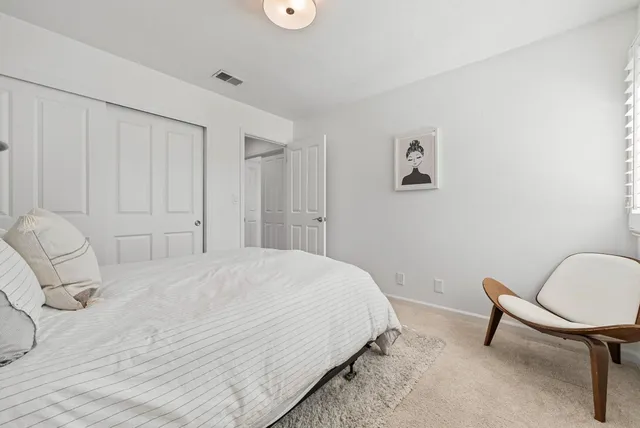 a bedroom with a bed a chair and painting on the wall