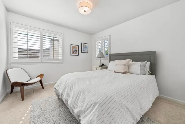 a bedroom with a bed a chair and next to a window