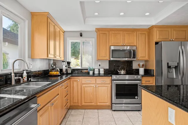 a kitchen with stainless steel appliances granite countertop a stove top oven a sink dishwasher a refrigerator and a microwave